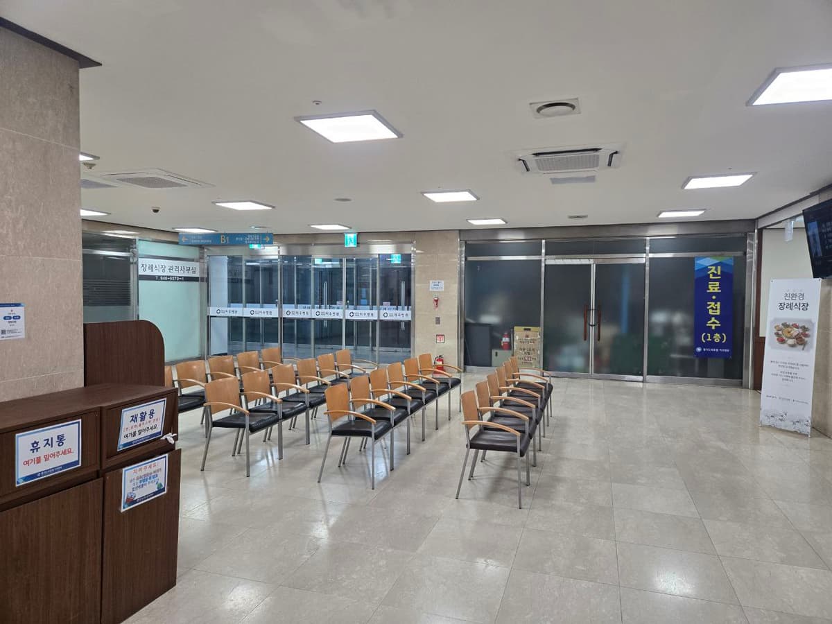 파주의료원장례식장 1층 추가 대기 공간과 출입구 방향 대기용 의자와 출입구 쪽이 보이는 장례식장 내부