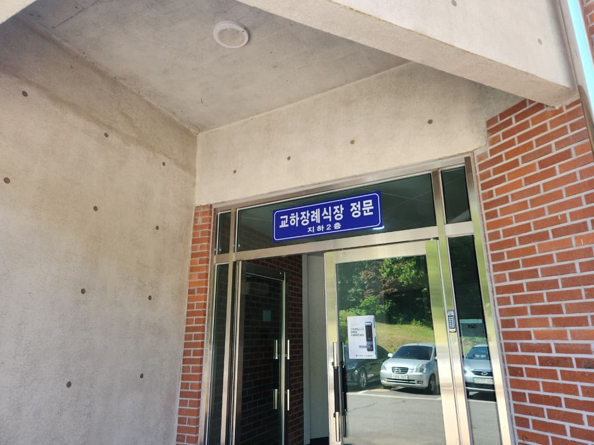 교하장례식장 정문 입구 전경 붉은 벽돌 외벽과 유리문이 있는 교하장례식장 정문 입구 모습