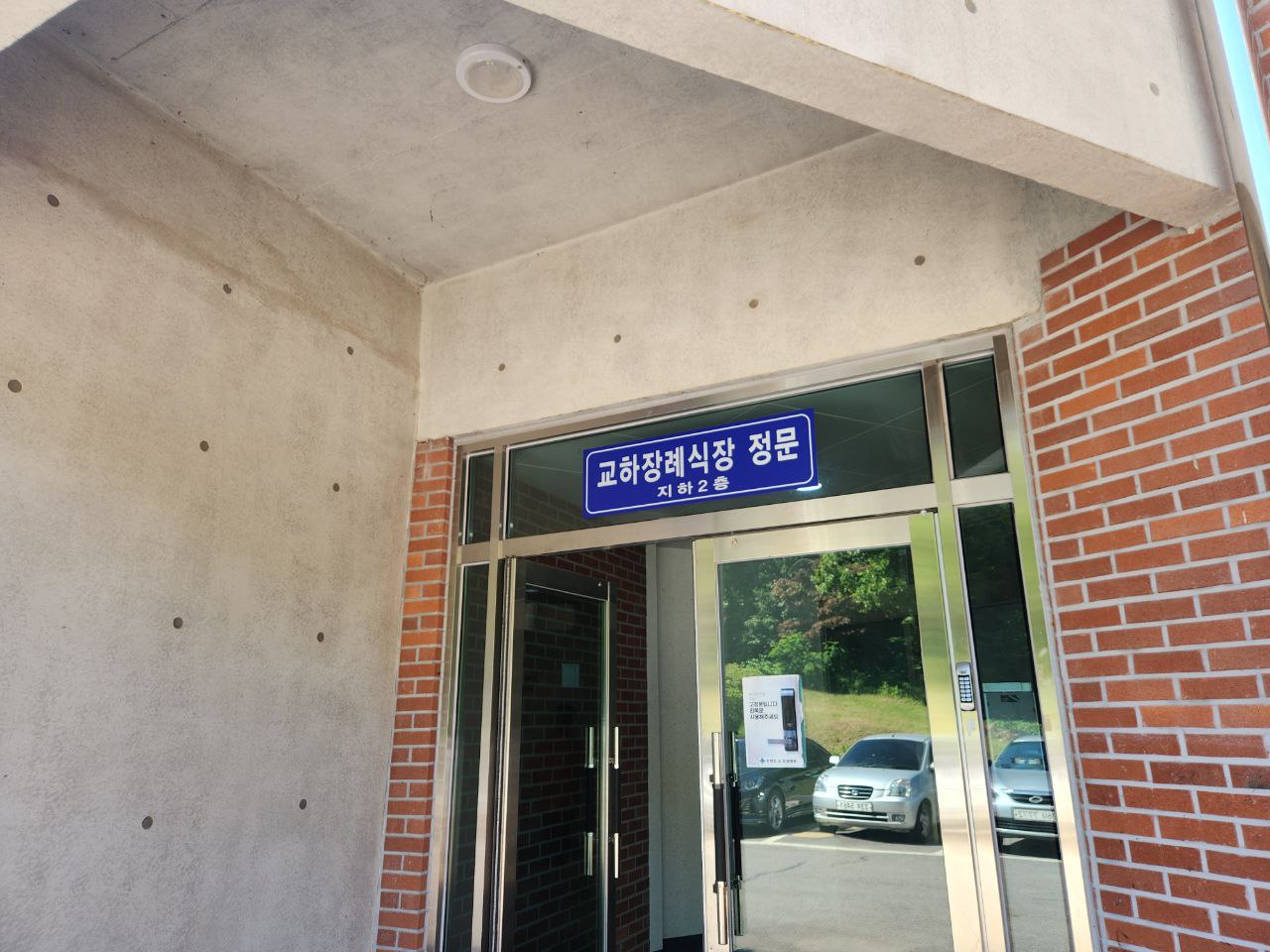 붉은 벽돌 외벽과 유리문이 있는 교하장례식장 정문 입구 모습